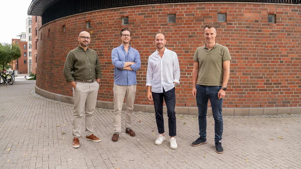 Four men standing in front of a wall